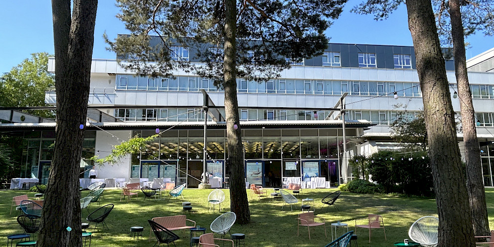 Außenansicht auf das Tagungszentrum Max Green mit Bäumen und Outdoormöbeln im anliegenden Garten