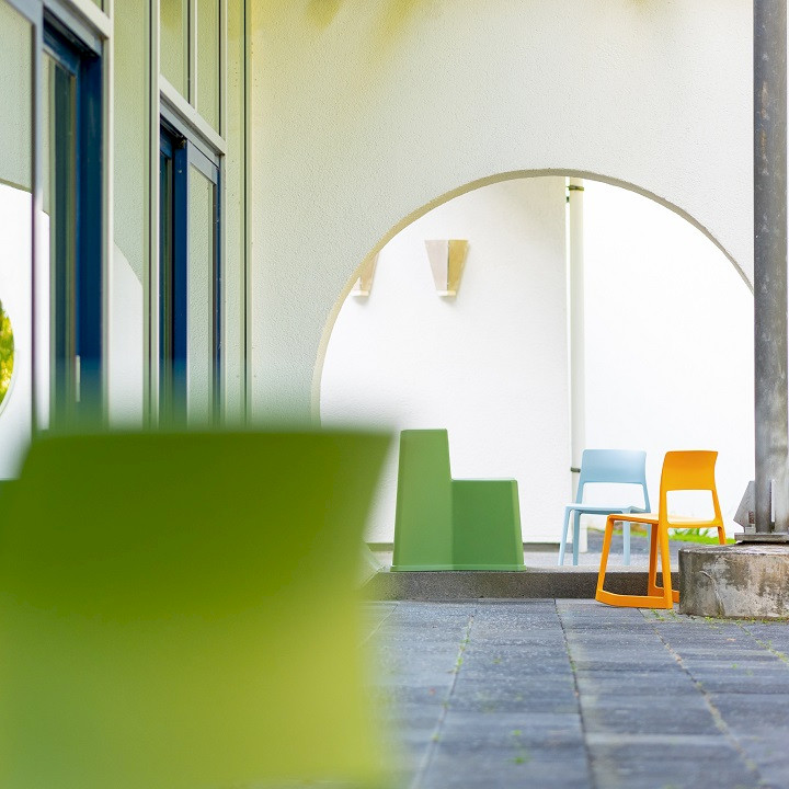 Eine Terrasse mit verschiedenfarbigen Outdoor-Möbeln vor einer Glasfront