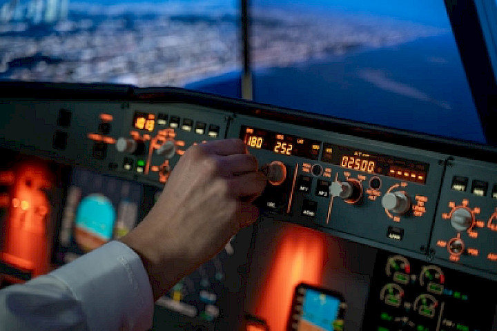 Eine Hand bedient einen von vielen Knöpfen in einem Flugzeug-Cockpit während eines Flugs